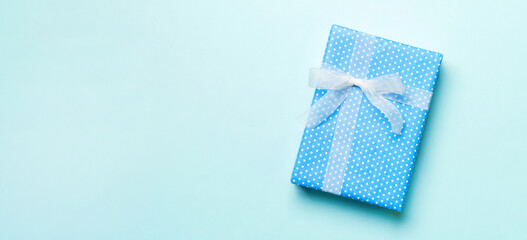 Top view Christmas present box with white bow on blue background with copy space
