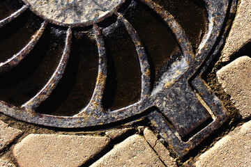Metal sewer manhole cover on a stone road. Urban stormwater system. close-up