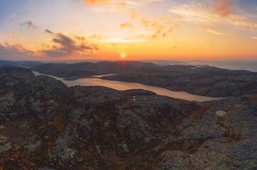 Aerial view from the top of a rocky mountain over Lapland landscape, lake and Barents Sea. Autumn sunset arctic panoramic landscape