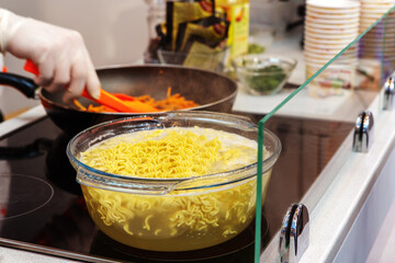 Cooking quick noodles in a glass pan. Inexpensive food in a simple way. Close-up.