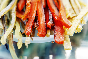 Dried fish in the shape of a straw. Salted fish delicacies on a plate. Close-up.