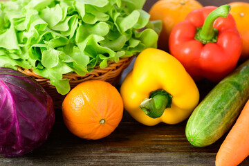 Colorful fresh vegetables on wooden table (cabbage, lettuce, bell pepper, cucumber, carrot and orange)