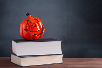 Book stack with scary pumpkin lantern, Halloween decor against grey stone background, copy space
