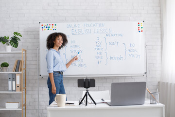 Online education and English lesson. Friendly african american woman points to blackboard