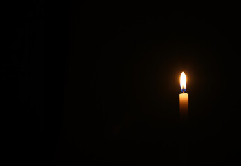 One yellow candle burns in black background