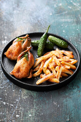 Grilled quails with fried parsnips or potatoes and pickled cucumbers, selective focus