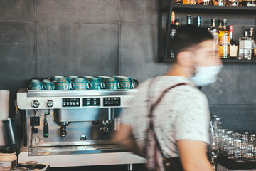 Bartender in a protective medical mask in a cafe. Space for a logo or sign. Figure in motion