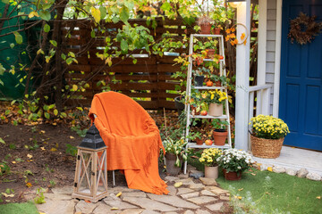 Cozy Autumn patio with chair, plaid, wooden lantern, potted chrysanthemums and pumpkins. Halloween....