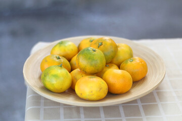 Wooden bowl with tangerines on a table. Selective focus.