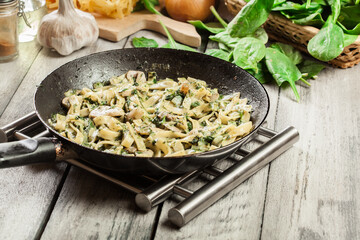 Tagliatelle pasta with spinach and mushrooms on a pan.