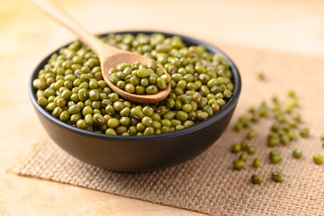 Mung bean in a bowl and spoon on wooden background