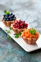 Healthy coconut tartlets with custard and fresh berries, selective focus