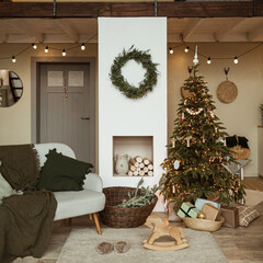 Modern interior design concept. Comfortable cozy living room decorated with Christmas tree with gifts, wreath frame, fireplace, sofa, carpet. Christmas / New Year celebration decorations.