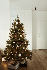 Beautiful Christmas tree with toys, baubles, garland and homemade paper gift boxes.