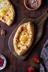Adjarian khachapuri on a wooden table, top view, dark photo.