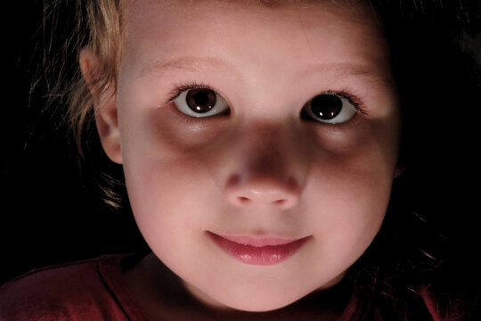   child's face close up in the dark, concept mystery in the child's soul                 ,soft focus and light blur