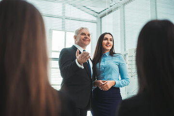 boss and young speaker standing together in front of business presentation listeners