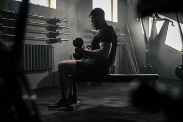 Serious Sportsman Sit on Bench and Lift Dumbbells .