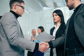 smiling business partners shaking hands with each other.