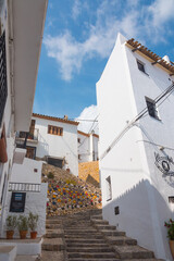 Beautiful narrow street in Altea, Costa Blanca, Valencian Community, Spain. Historical center. Stone stairs going up. Vertical shot. White greek-like architecture.