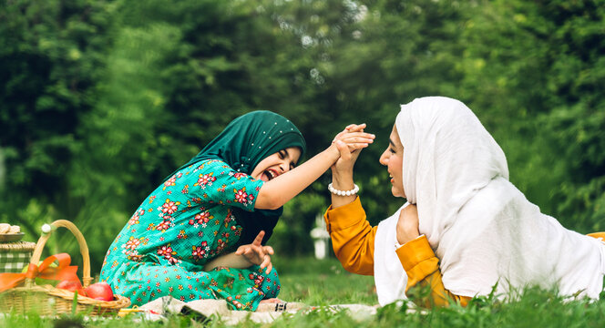 Portrait of happy religious enjoy happy love asian family arabic muslim mother and little muslim girls child with hijab dress smiling and having fun moments good time in summer park
