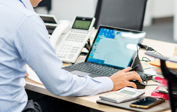 オフィスワーク　ノートパソコンのモニターを見ながら作業するビジネスマン　