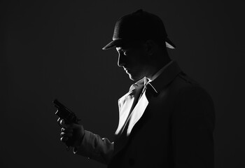 Old fashioned detective with revolver on dark background, black and white effect