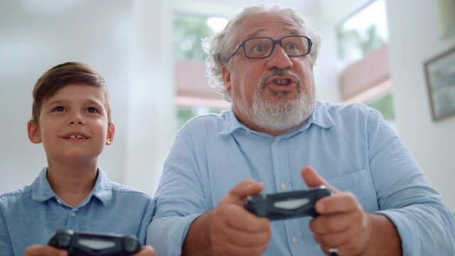 Portrait of cheerful grandson and grandfather playing video game in living room
