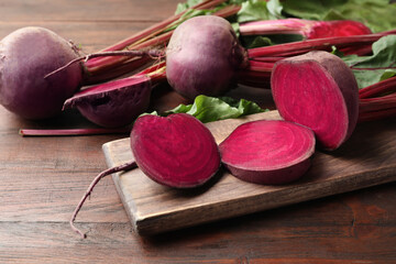 Cut and whole raw beets on wooden table
