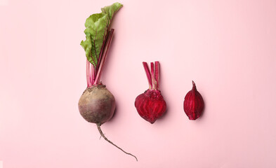 Whole and cut fresh red beets on pink background, flat lay