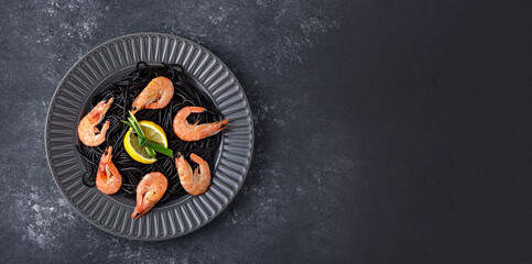 top view black pasta with ink cuttlefish, Royal shrimp and lemon slices in gray plate on gray background with copy space