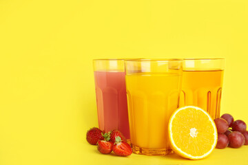 Glasses of delicious juices and fresh fruits on yellow background. Space for text
