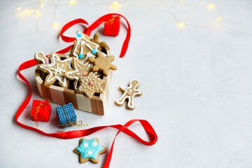 Homemade gingerbread cookies, colorful boxes with gifts and a red ribbon on a light background with side text space.