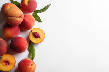 Fresh ripe peaches and green leaves on white background, flat lay. Space for text