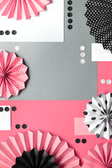 Creative pink background with folded paper fans and confetti on black, pink and white.