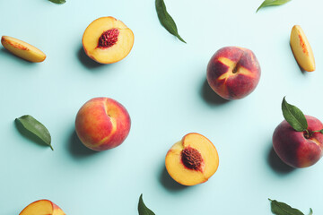 Fresh ripe peaches and green leaves on light blue background, flat lay