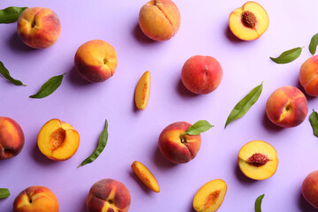 Fresh ripe peaches and green leaves on violet background, flat lay