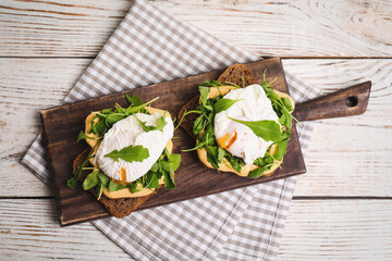 Delicious sandwiches with arugula and egg on white wooden table, top view