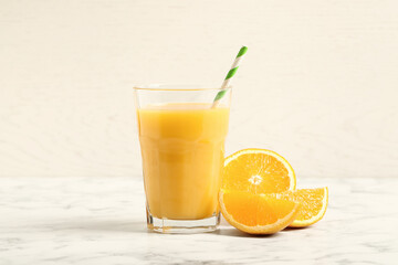 Glass of orange juice and fresh fruits on white marble table