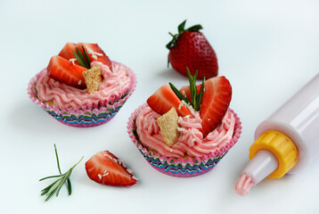 Cupcake with pink cream and strawberries on a white background