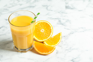 Glass of orange juice and fresh fruits on white marble table
