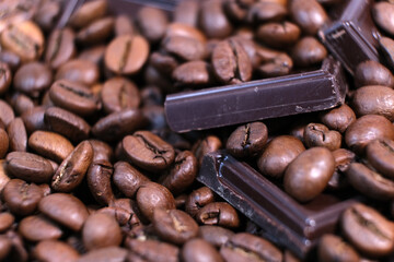 Close-up of dark roasted coffee beans and chocolate background.