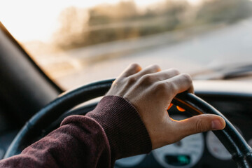 concept of working as a driver, hand on the steering wheel at sunset.
