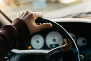 concept of working as a driver, hand on the steering wheel at sunset.