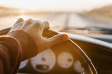 concept of working as a driver, hand on the steering wheel at sunset.