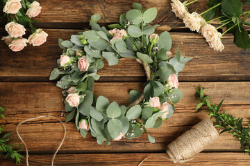 Flat lay composition with wreath made of beautiful flowers on wooden table
