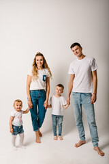 Family portrait of parents and children in denim casual style clothes. Fashion models on white background. Smiling young mother and father with daughter and son posing together.