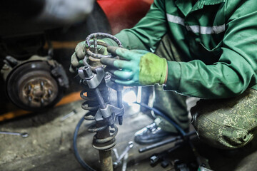 Auto mechanics compress the spring with zip ties to replace the shock absorber. Car suspension repair.