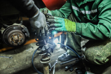 Auto mechanics compress the spring with zip ties to replace the shock absorber. Car suspension...