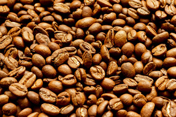 Roasted arabica coffee beans scattered in a heap on the table.